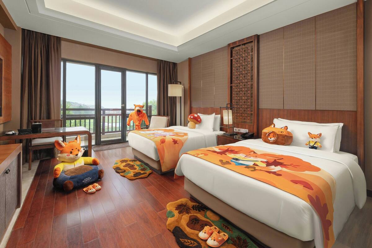 A hotel room with two beds, a desk, and a balcony.
