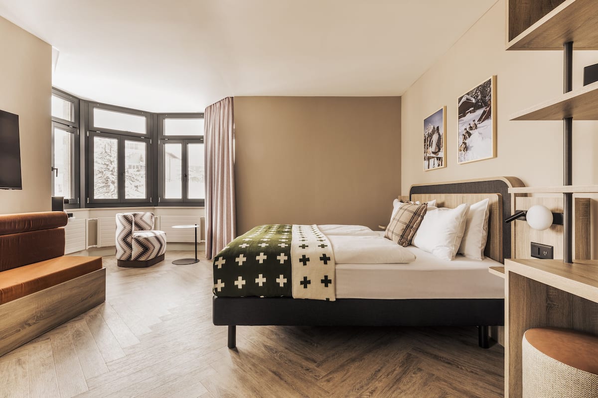 A modern bedroom with a large bed, a sofa, and a TV.