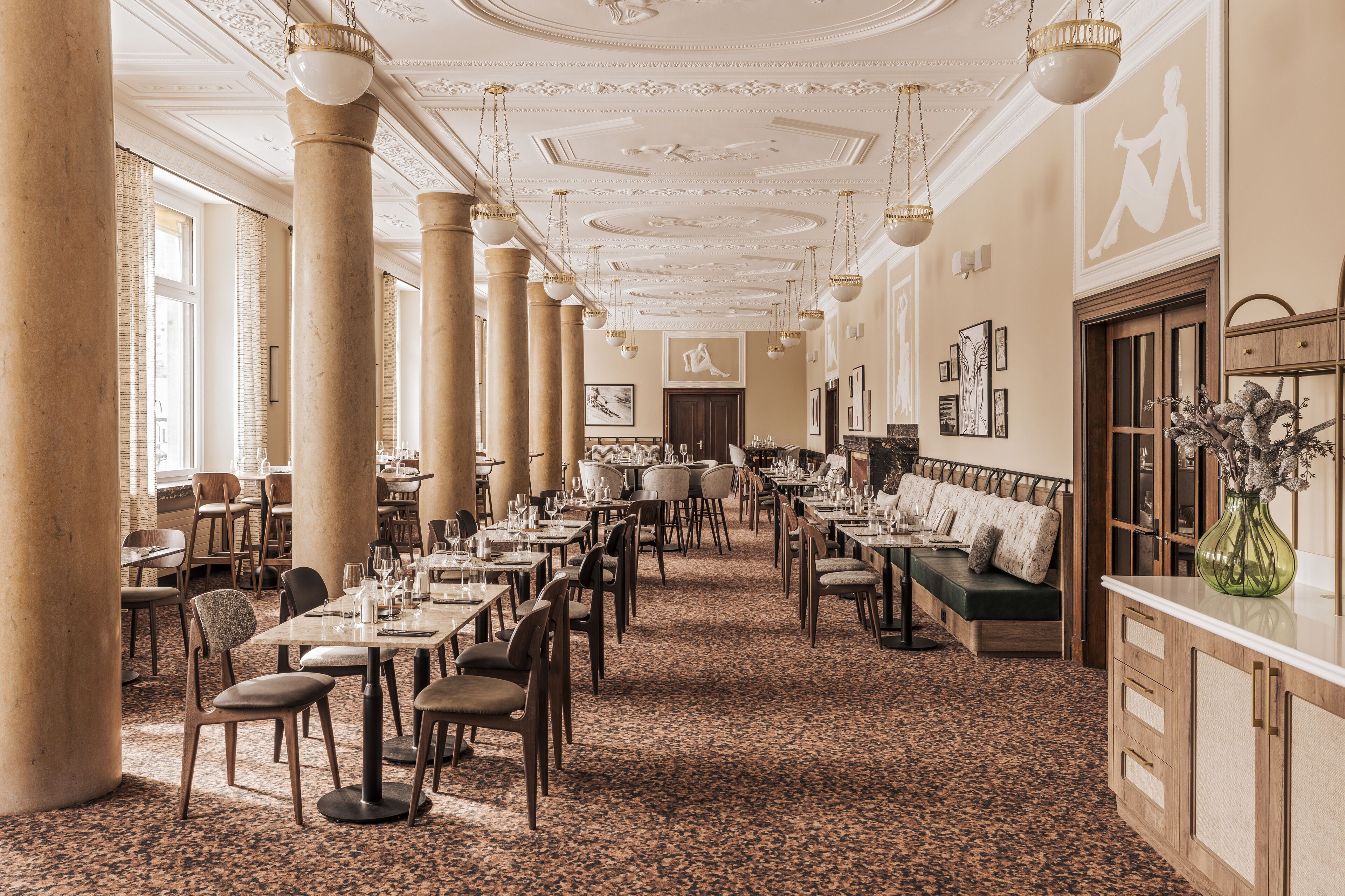 A spacious dining area with high ceilings, large windows, and a central seating area.