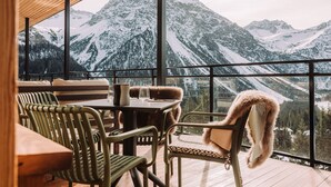 Un rincón acogedor con una mesa y sillas, con vistas a montañas cubiertas de nieve.