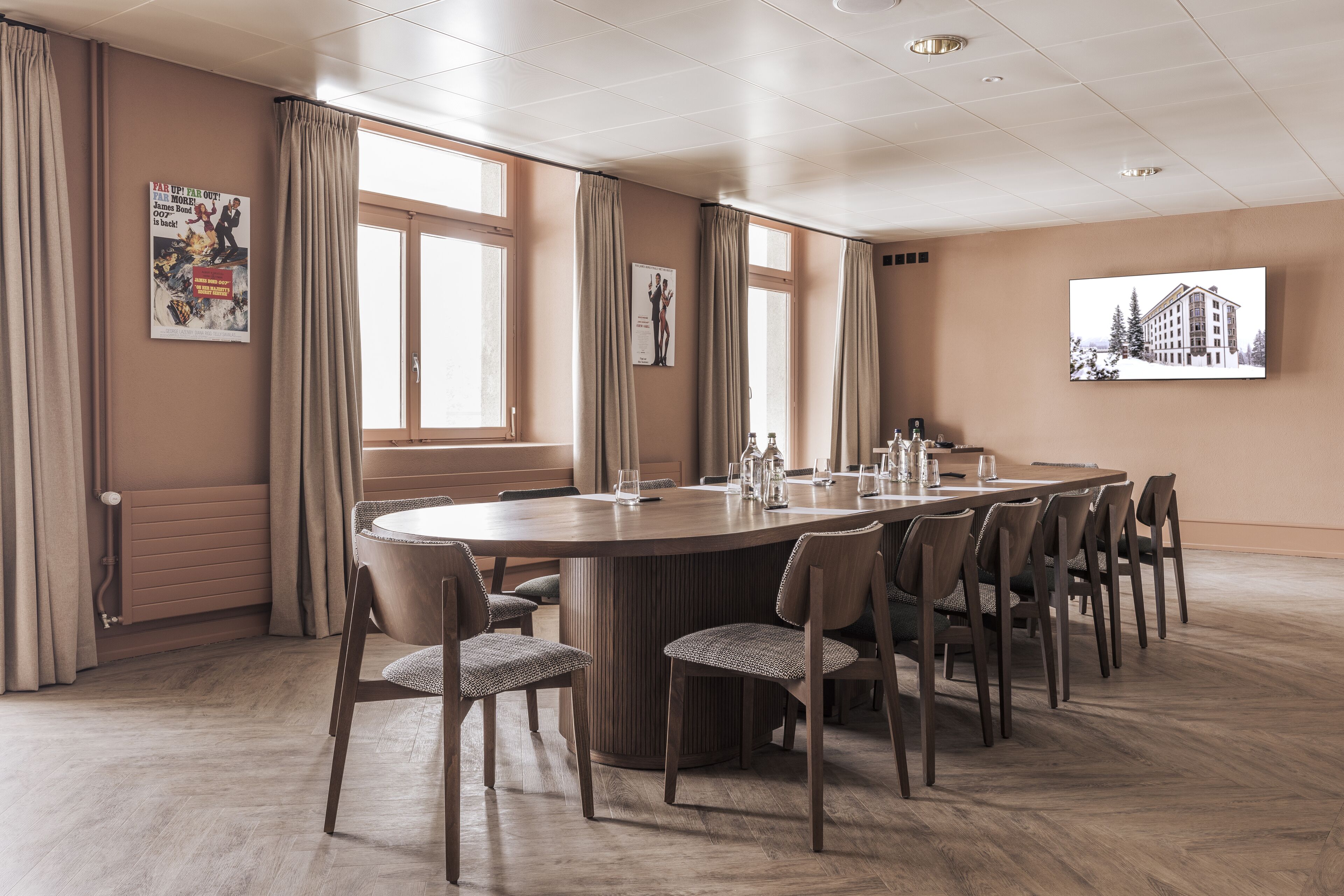 Une salle de conférence dotée d’une grande table ovale, de murs de couleur beige et de grandes fenêtres avec des rideaux.