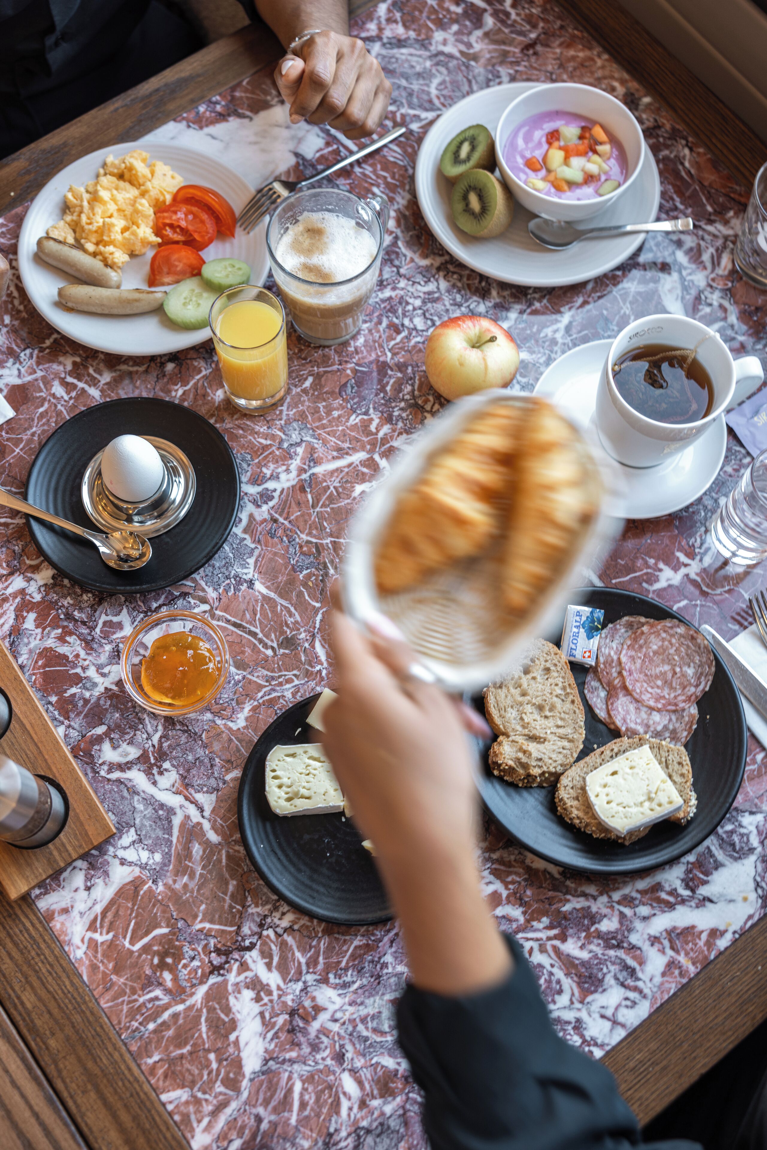 A breakfast table with various food items and a cup of coffee.