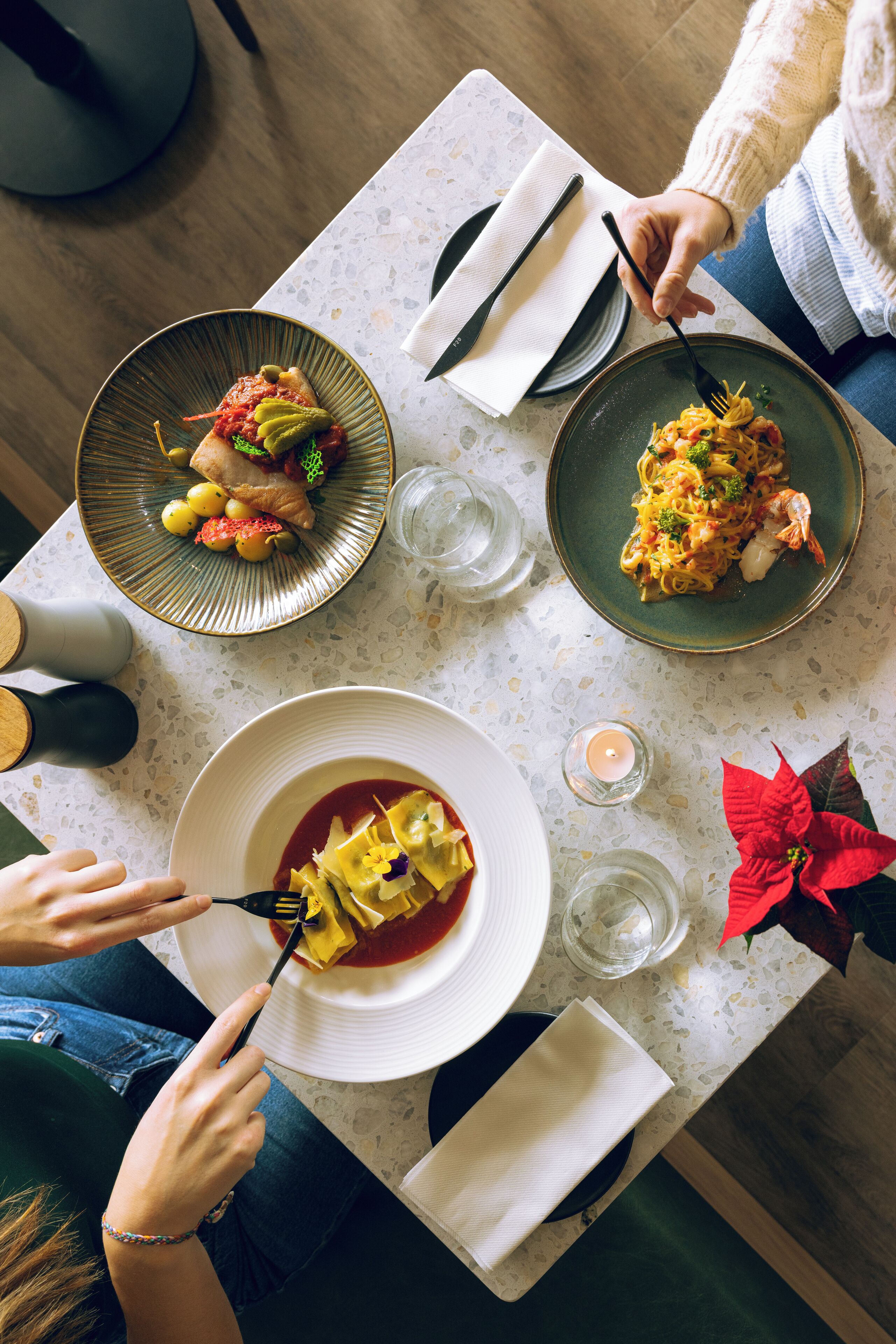 A dining table with plates of food, cutlery, and a candle.