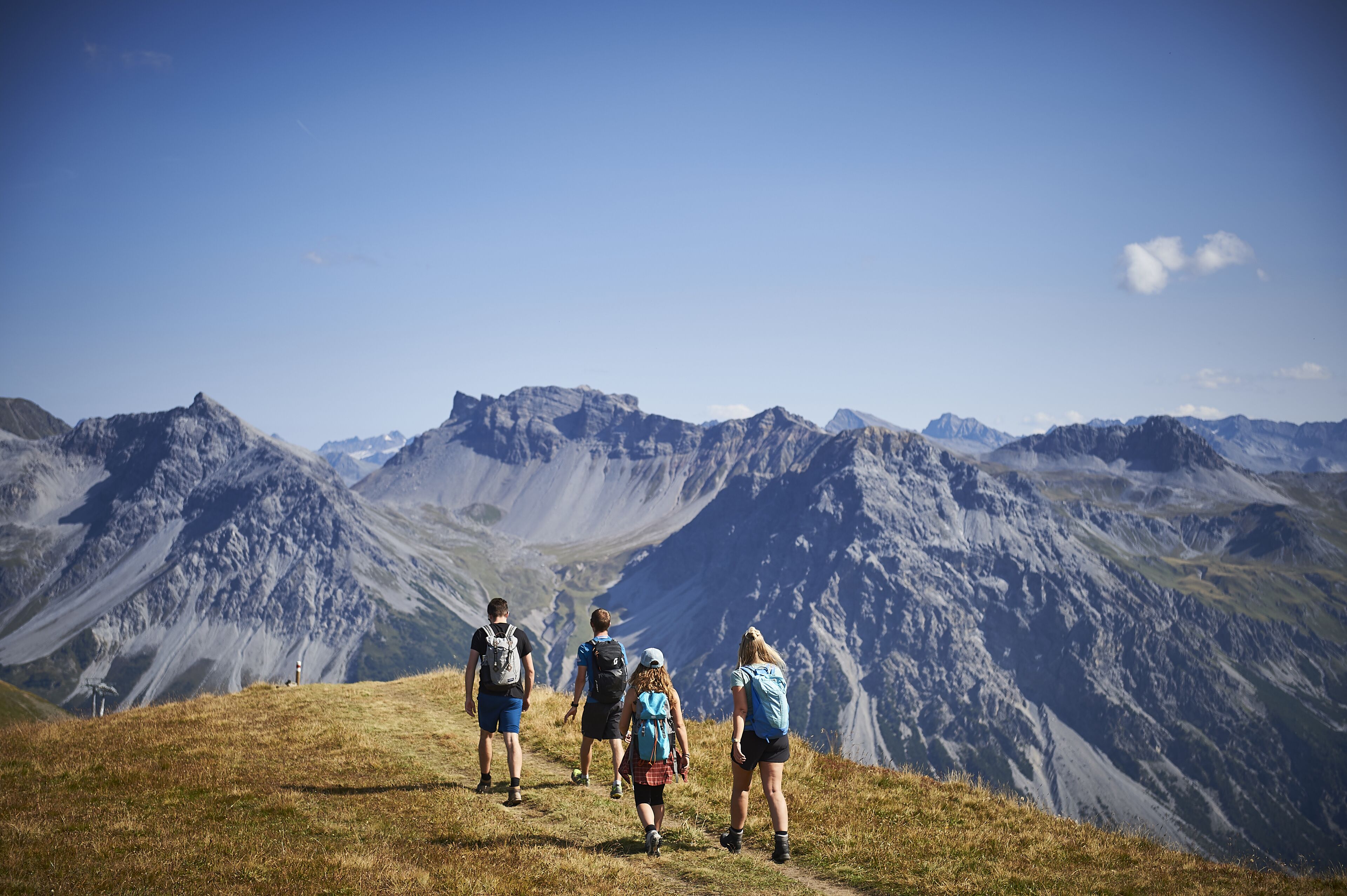 Un gruppo di escursionisti su un sentiero di montagna, con vista chiara su montagne impervie sullo sfondo.