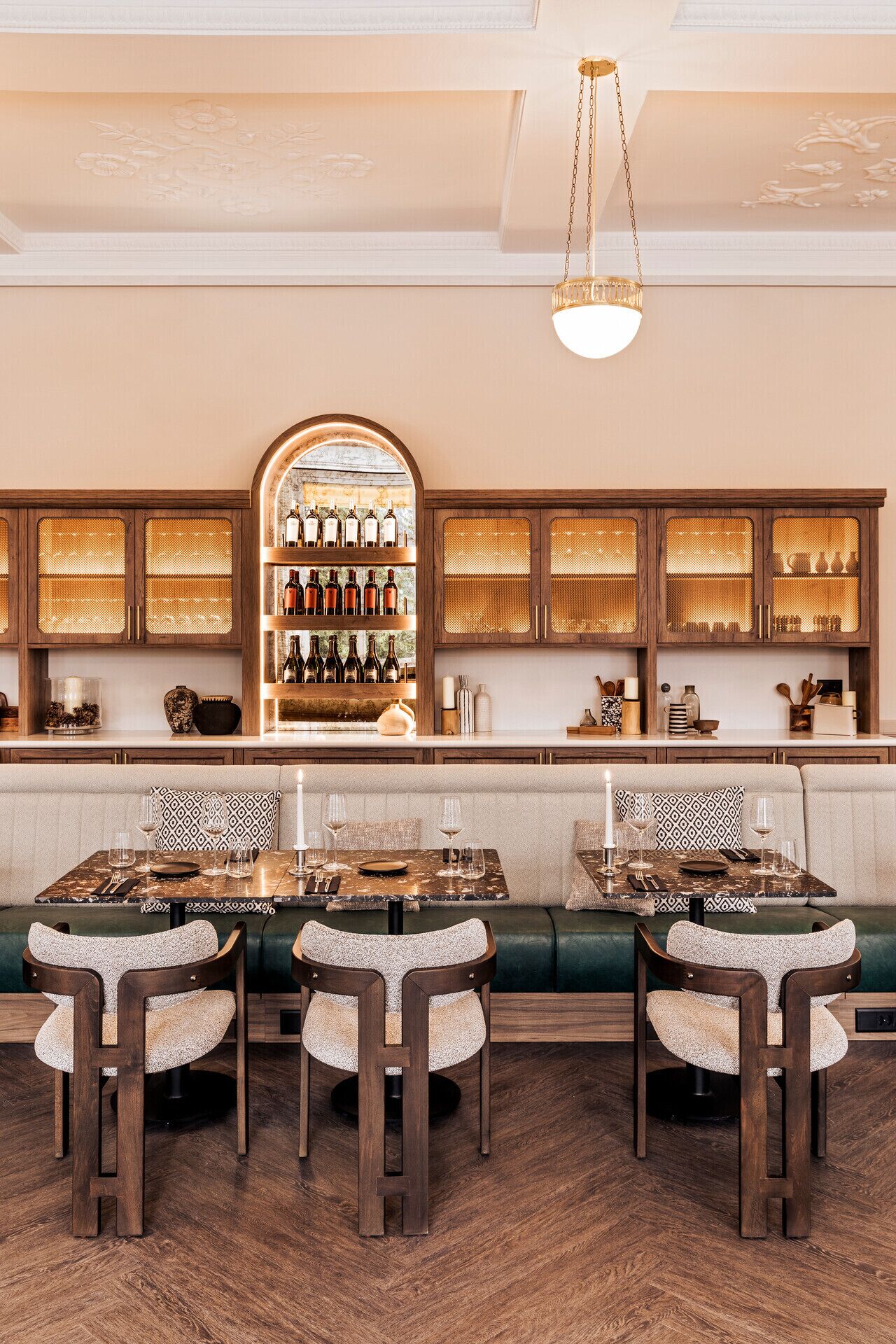 A restaurant with a bar area, wooden cabinets, and a green cushioned bench.