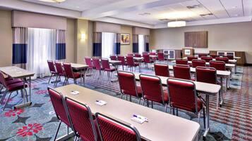 Une salle de conférence dotée de plusieurs tables et chaises, d’un sol recouvert de moquette et d’un plafond pourvu d’un éclairage encastré.