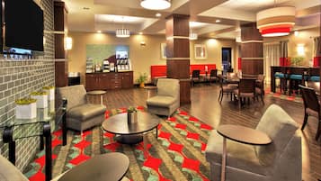 A hotel lobby with seating areas, a reception desk, and a television screen.
