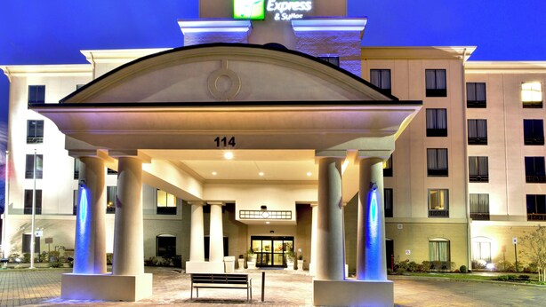 A hotel entrance with a covered walkway, columns, and a sign indicating it's a Holiday Inn Express & Suites.