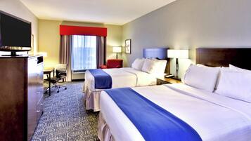 A hotel room with two beds, a desk, a television, and a window with curtains.