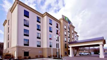 A multi-story hotel with a flat facade, a covered parking area, and a flagpole with multiple flags.