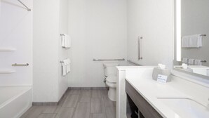A modern bathroom with a toilet, a handrail, a towel rack, and a sink with a mirror. - Holiday Inn Express & Suites Oak Ridge by IHG (Oak Ridge)