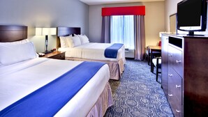A hotel room with two beds, a TV, a desk, and a dresser.