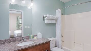 A bathroom with a granite sink, white toilet, and a shower with a glass door.