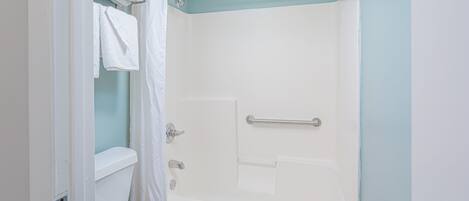 A bathroom with a white toilet, a bathtub with a shower curtain, and a towel rack.