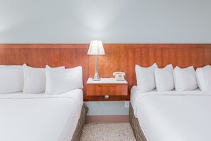 A hotel room with two beds, a nightstand with a lamp, and a telephone. - Bikini Beach Resort (Panama City Beach)