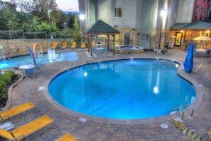 Una piscina circular con hidromasaje, rodeada de sillas amarillas y un pabellón.