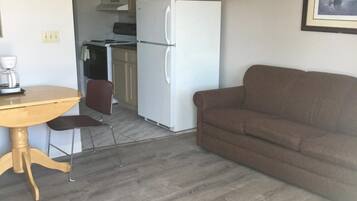 Un espacio habitable compacto con kitchenette, comedor y sofá.