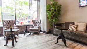 A modern lobby with a sofa, armchairs, and a table. A large window offers a view of the street. - Ivy Boutique Hotel (Chicago)