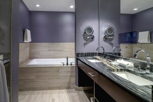 A modern bathroom with a bathtub, two sinks, and a large mirror.