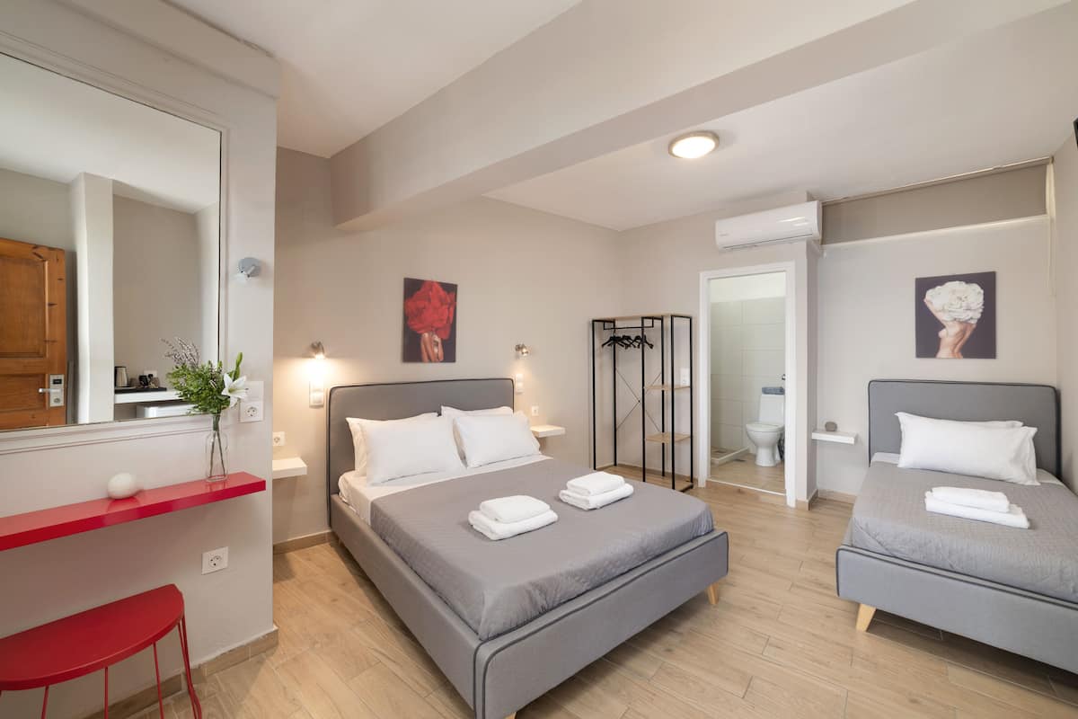 A modern hotel room with two beds, a red chair, a small table, and a mirror.