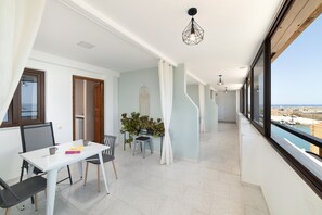 Um apartamento moderno com varanda, área de refeições e vista para o mar.