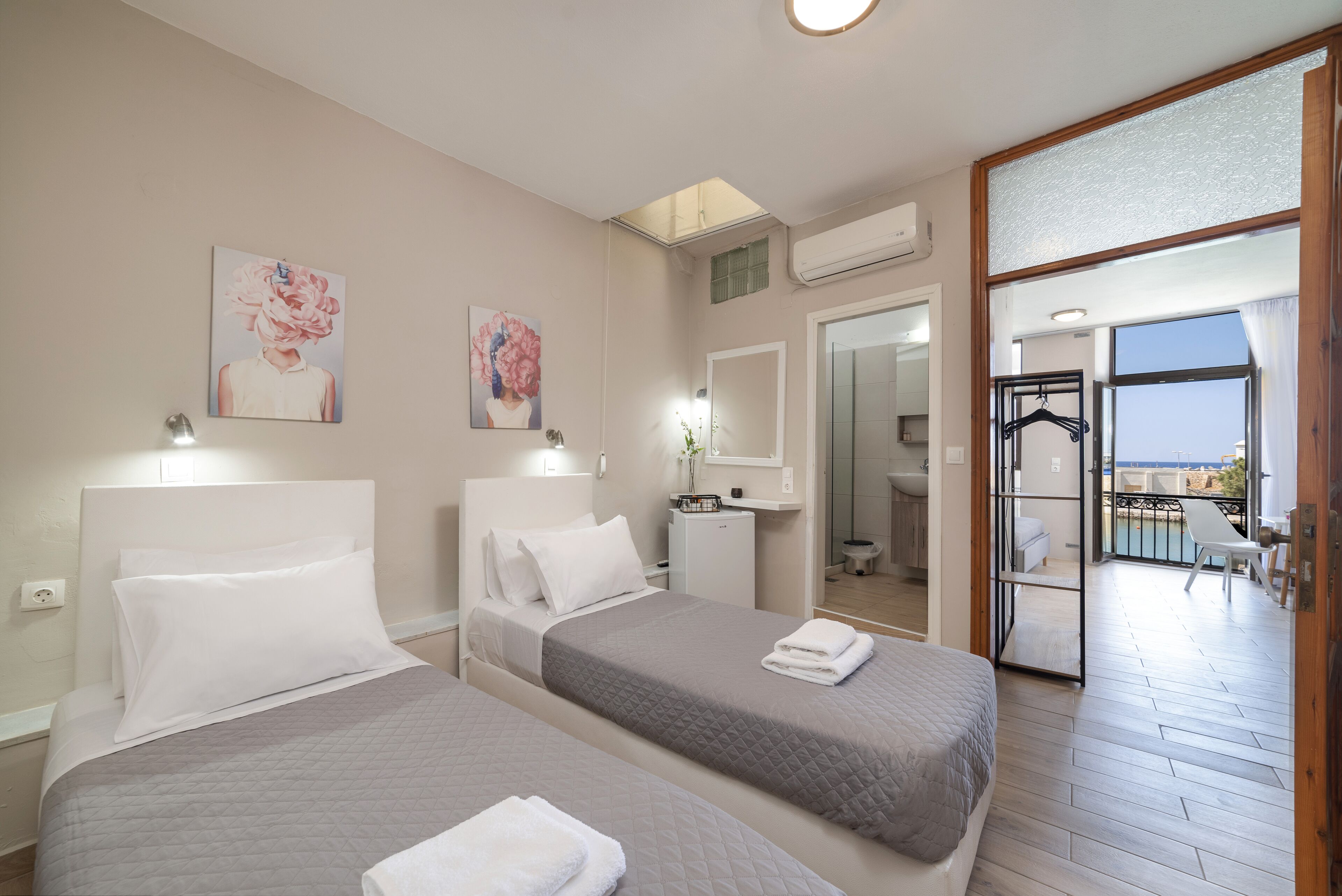 Een hotelkamer met twee bedden, een badkamer en een balkon met uitzicht.