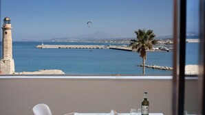 A balcony with a table, a chair, a bottle of wine, and an open book. - Faros Beach Hotel (Rethymno)