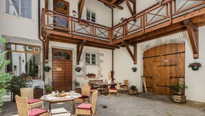 Un patio de estilo europeo tradicional con vigas de madera, una puerta de madera y mobiliario de mimbre.