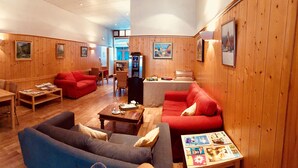 Una habitación acogedora con paredes de madera, un sofá azul, un sofá rojo, una mesa de madera y una mesita de centro.