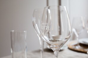 Une table sur laquelle sont disposés plusieurs verres à vin transparents, dont l’un présente en évidence l’inscription « vins du Lura ».