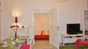 Una habitación de hotel con comedor, una cama, un televisor y una araña.