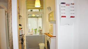 Una cocina compacta con lavadora, microondas y lavamanos.