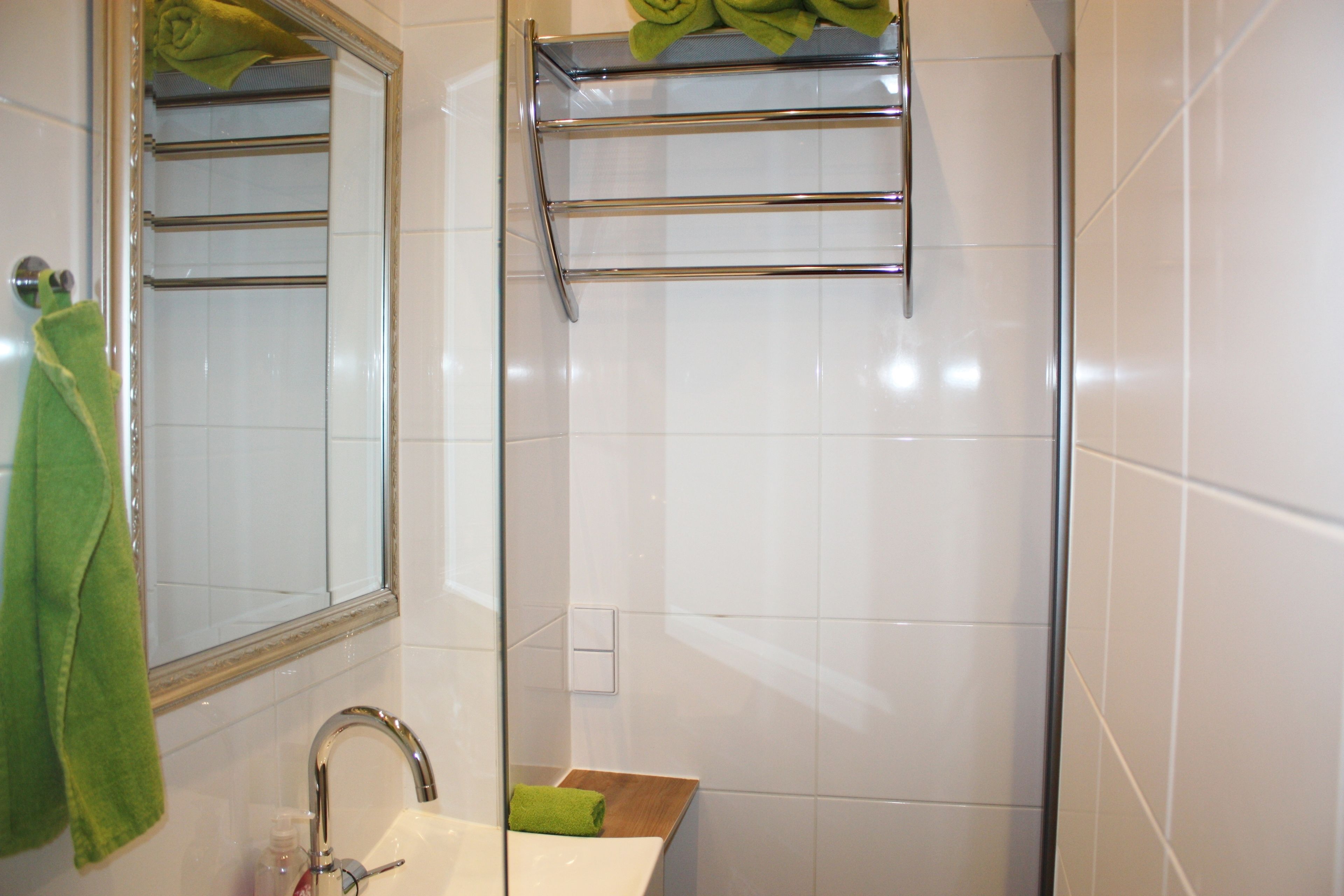 Een badkamer met een spiegel, wastafel en handdoekhouder.