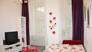 Un dormitorio con una cama, un televisor sobre un mueble, una mesita y un armario.