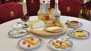 Une table à manger avec divers plats, notamment du fromage, une bouteille de spiritueux et des desserts.