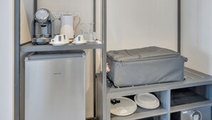 A compact kitchenette with a coffee maker, a small refrigerator, and a suitcase on a shelf. - Captain Karas Collection (Paralimni)