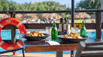A dining table with two plates of food, a life preserver, and bottles of beverages.