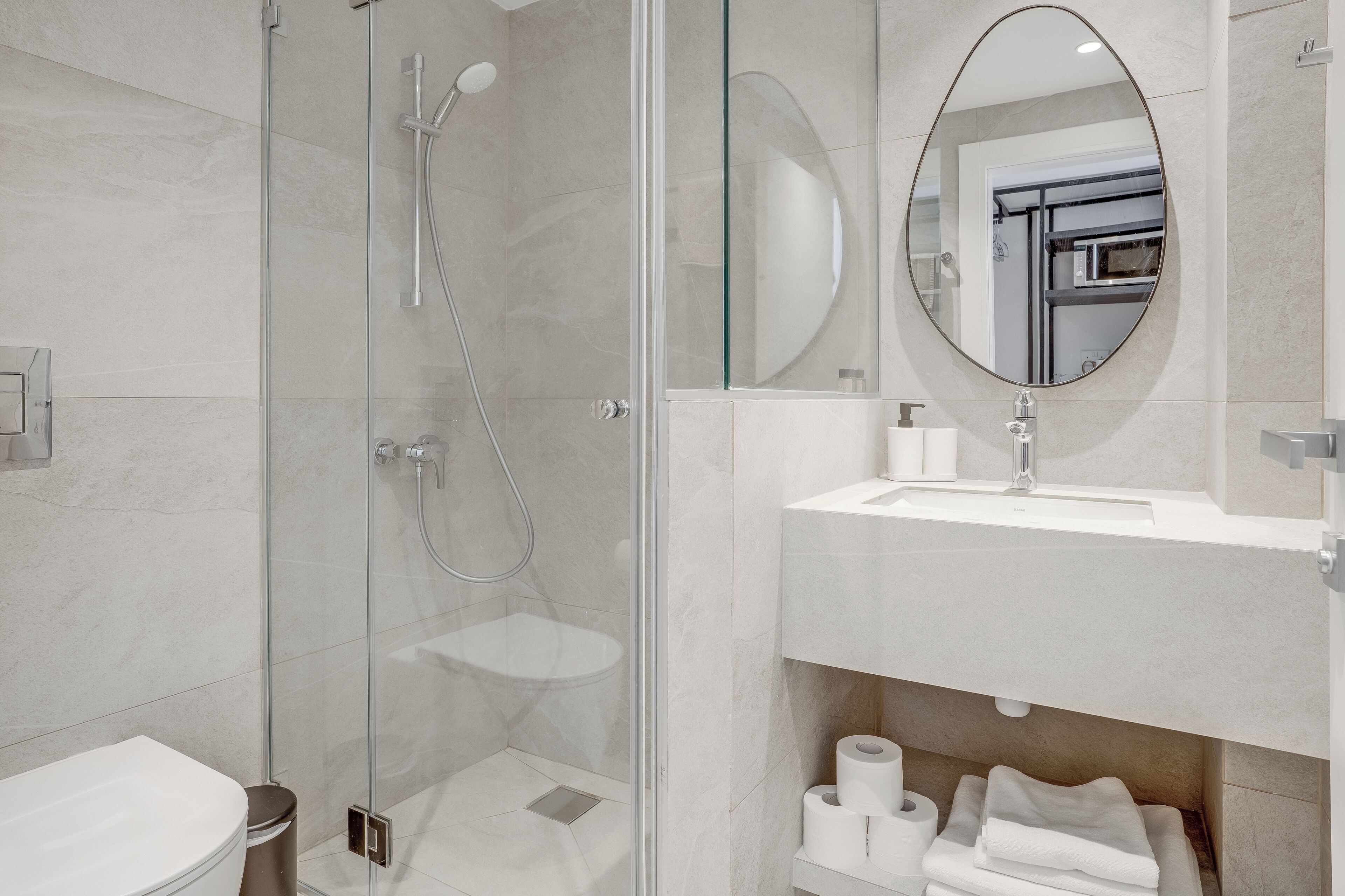 A modern bathroom with a glass-enclosed shower, a white sink, and a mirror.