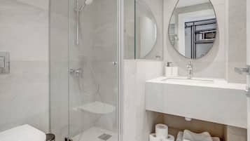 A modern bathroom with a glass-enclosed shower, a white sink, and a mirror.