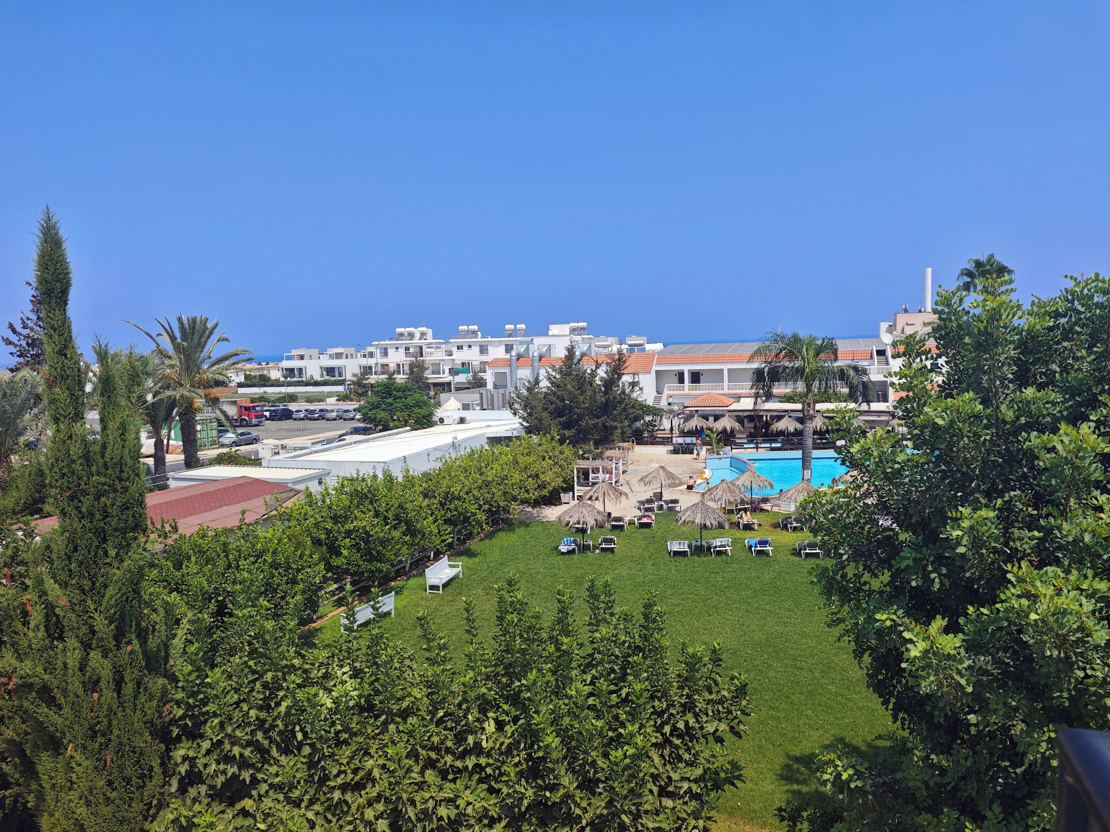 Een resort met een zwembad, ligbedden en uitzicht op zee.