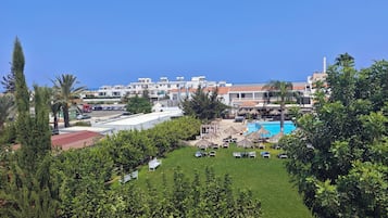 A resort with a swimming pool, lounge chairs, and a view of the sea.