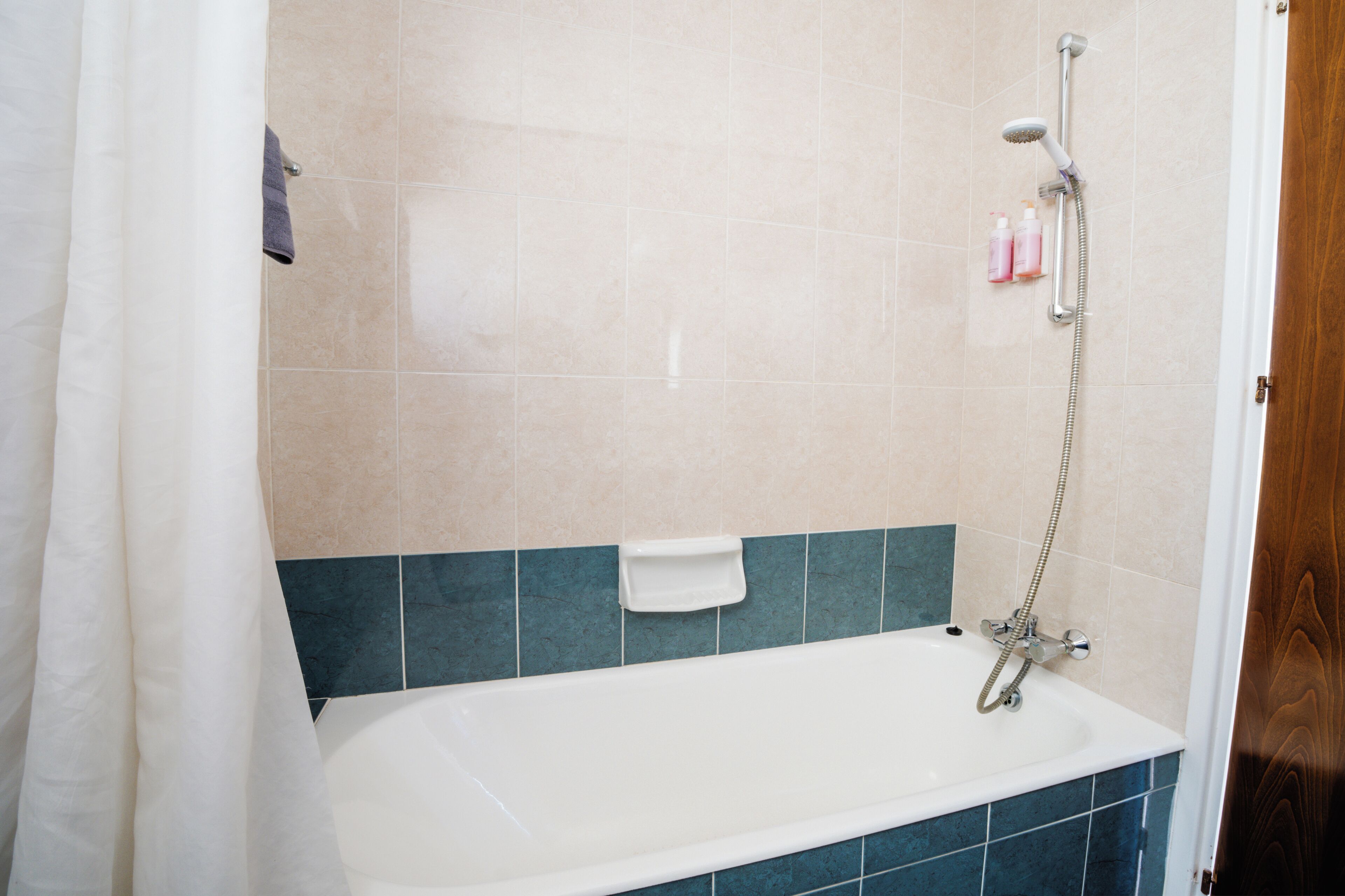 Un baño con bañera, ducha y paredes de azulejos.