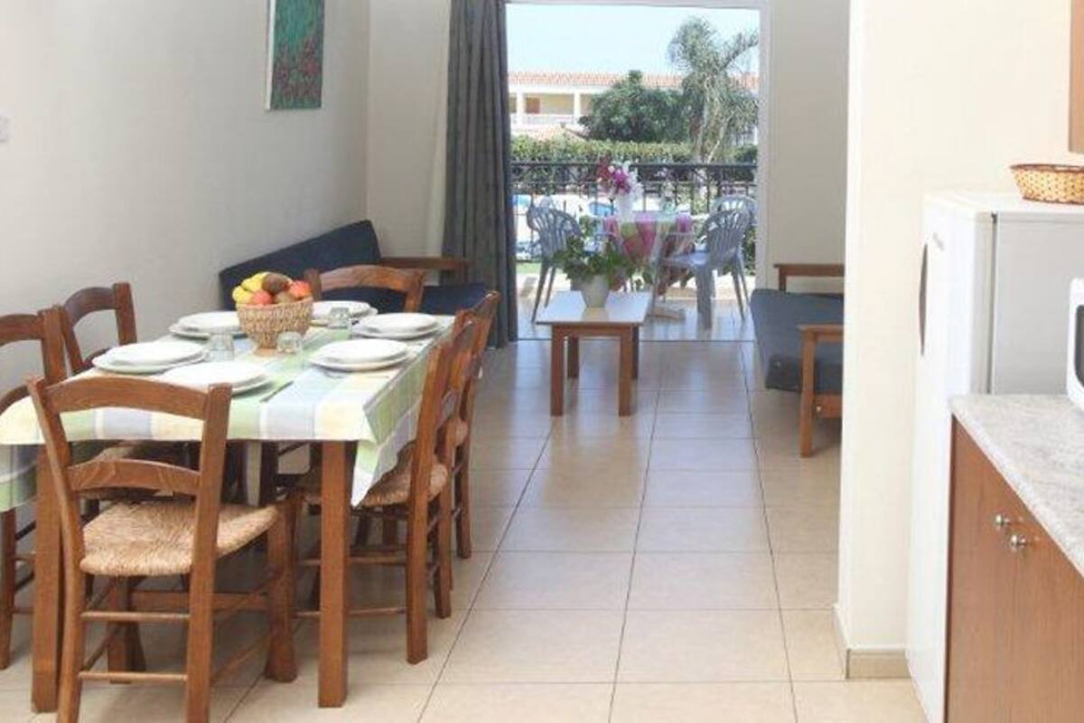 A dining area with a table set for four, a kitchen with a microwave and a toaster, and a view of a balcony with outdoor furniture.