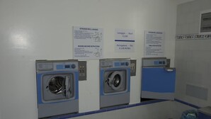 A laundry facility with three washing machines, each with a control panel and a sign above indicating washing and drying instructions. - Angelina Residence (Maiori)