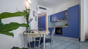 A modern kitchen with blue cabinets, a wooden dining table, and chairs. - Angelina Residence (Maiori)
