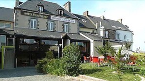 A hotel with a restaurant on the ground floor, featuring a gravel driveway and outdoor seating area. - Hôtel Beau Rivage, Restaurant L'Eveil des Sens (Le Vivier-sur-Mer)