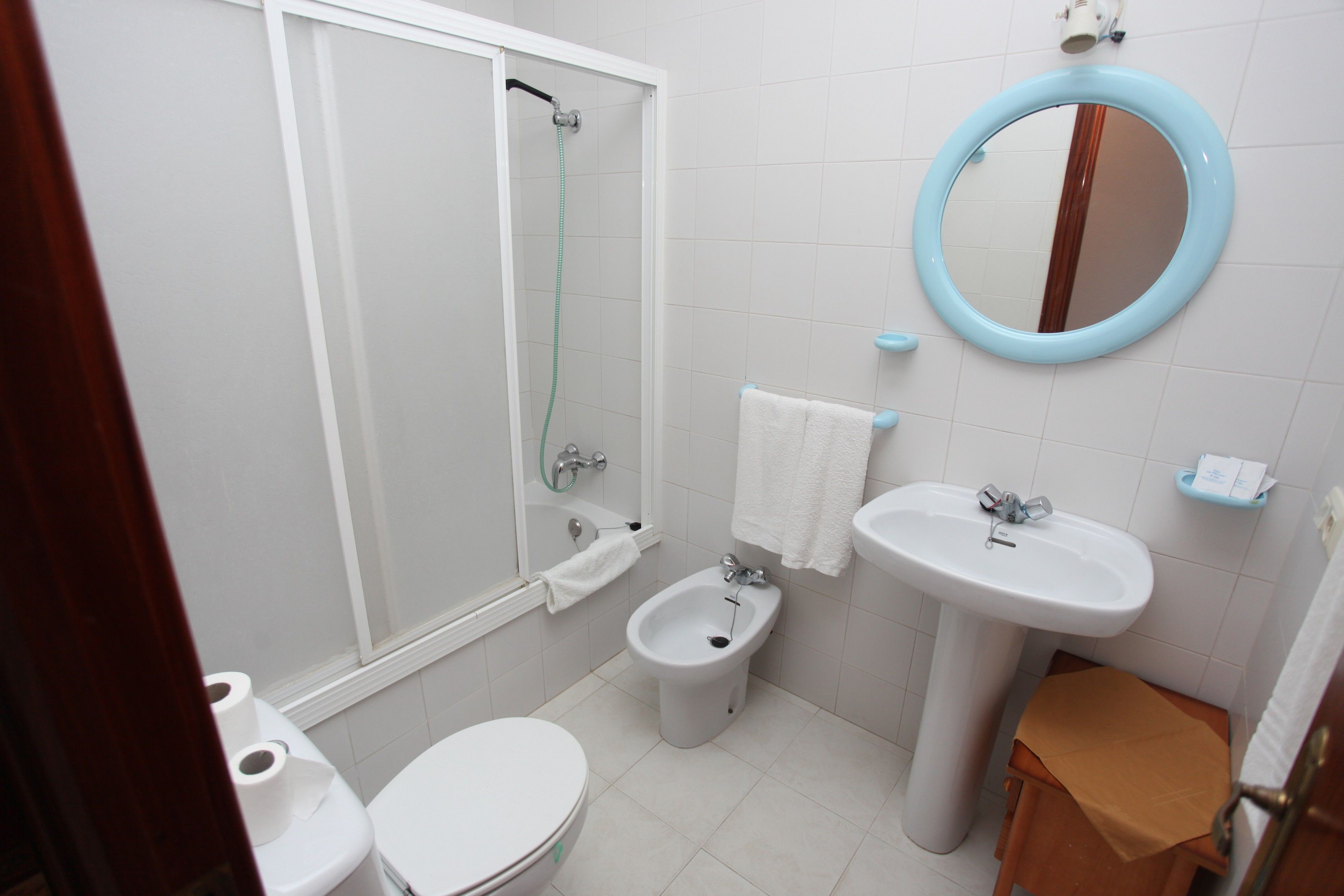 A bathroom with a toilet, bidet, sink, mirror, and shower.