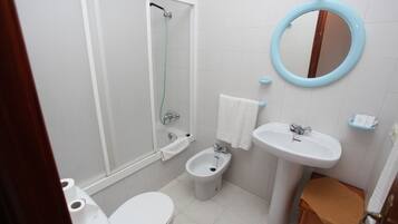 A bathroom with a toilet, bidet, sink, mirror, and shower.