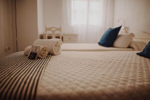 Una cama bien hecha con toallas enrolladas y un pequeño objeto sobre la cama.