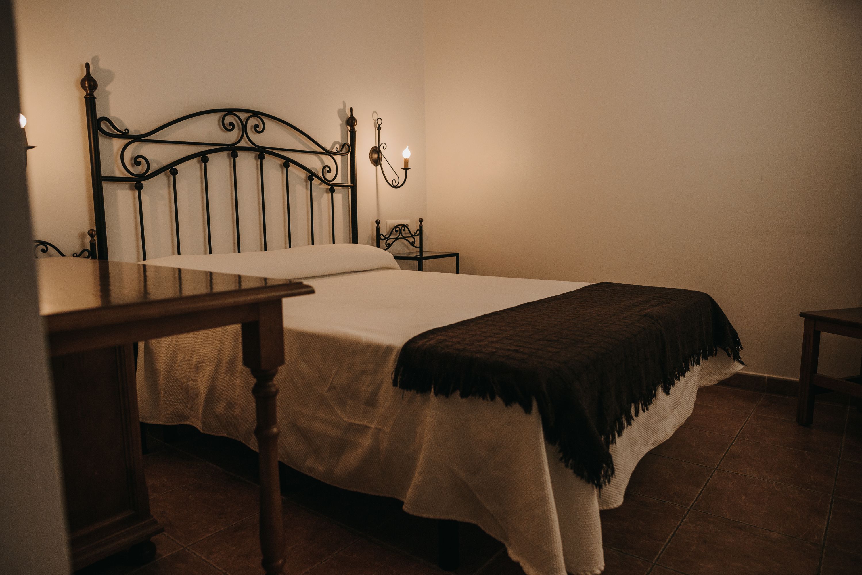 Un dormitorio con una cama, una mesita de noche y una mesita auxiliar.